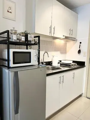 a kitchen with white cabinets and a microwave at Jazz Residence T2 Rm 405 Homey Muji Inspired Staycation Big Screen Cinema in Manila