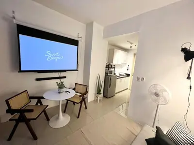 a living room with a table and a projection screen at Jazz Residence T2 Rm 405 Homey Muji Inspired Staycation Big Screen Cinema in Manila