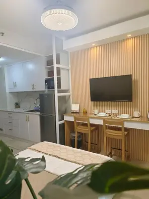 a kitchen with a table with chairs and a television at Cozy Simple Room by Metro Staycation in Manila