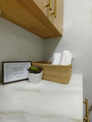 a bathroom counter with a basket of towels and a plant at Cozy Simple Room by Metro Staycation in Manila