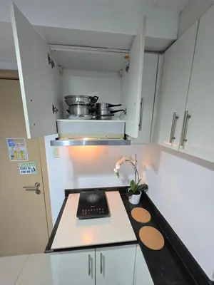 a kitchen with white cabinets and a counter top at MNM Place - Sea Residence 8D in Manila