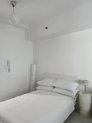 a white bedroom with a white bed with white pillows at The Bauhaus near Eastwood in Manila