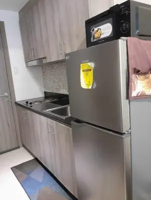 a kitchen with a stainless steel refrigerator with a yellow sticker on it at Condo Staycation Fame Residences T2 Mandaluyong Philippines in Manila