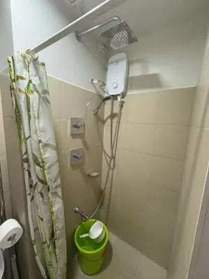 a bathroom with a shower with a green trash can at Cozy Haven 2 in Manila
