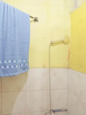 a shower with a blue towel hanging on a wall at Springbreak Residence in Manila