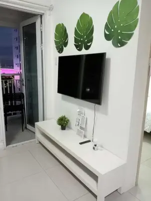 a living room with a tv on a white wall at MNM Place - Sea Residence 1B in Manila