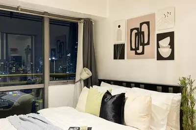 a bedroom with a bed with a view of a city at The Serene Escape Ph Rockwell Balcony View 1BR in Manila