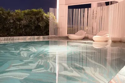 a swimming pool with two white chairs in a room at The Serene Escape Ph Rockwell Balcony View 1BR in Manila