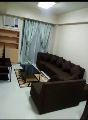 a living room with a brown couch and a window at Rqui Family Room Near Airport in Manila