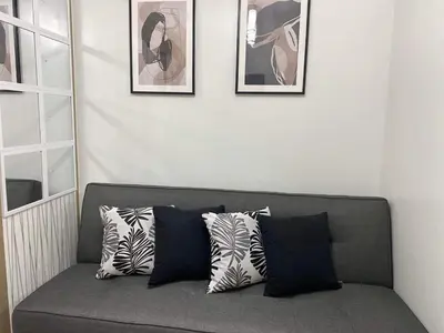 a gray couch with pillows on it in a room at Shore Residence a32 shortwalk Mall of Asia in Manila