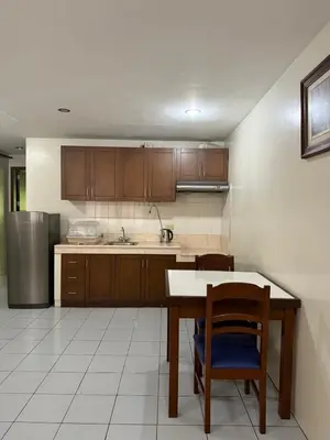 a kitchen with a table and chairs and a refrigerator at Joyce Apartelle San Juan in Manila