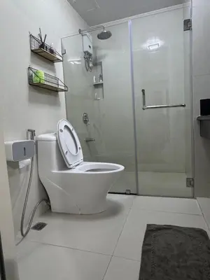 a white bathroom with a shower and a toilet at 2BR Resort Type condo w city view Sheridan in Manila