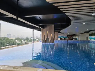 a large swimming pool with blue water in a building at The Hmlet Manila, Near Poblacion Makati Nightlife in Manila