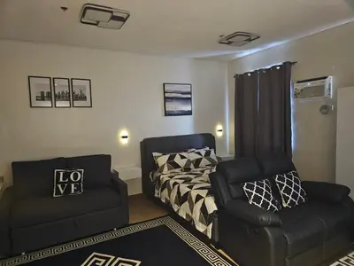 a bedroom with a bed and a chair at Harmony Suite Hope Trece Cavite in Trece Martires