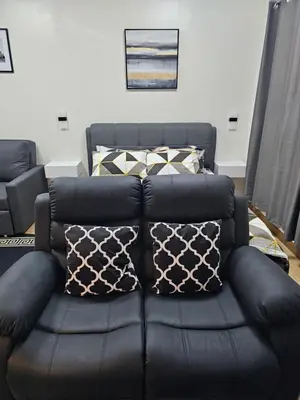 a black leather couch in a living room with pillows at Harmony Suite Hope Trece Cavite in Trece Martires