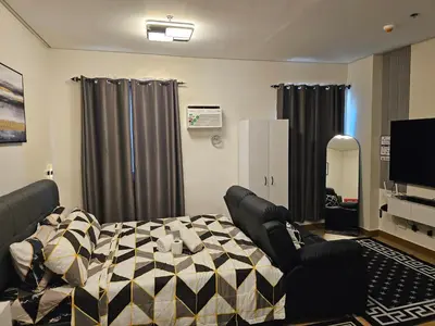 a bedroom with a bed and a tv and curtains at Harmony Suite Hope Trece Cavite in Trece Martires