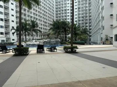 a courtyard with benches and palm trees and buildings at Beach Haven Condo in MOAs Shore Resort near Okada City of Dreams Solaire in Manila