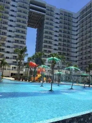 a large swimming pool with blue water and green umbrellas at Shell Residence in Manila