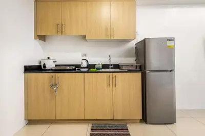 a kitchen with wooden cabinets and a stainless steel refrigerator at Sunrise & City View Steps from MOA & Bay Free WiFi in Manila