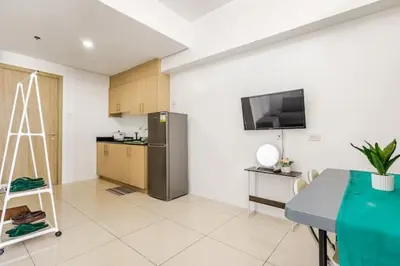 a living room with a kitchen with a refrigerator at Sunrise & City View Steps from MOA & Bay Free WiFi in Manila