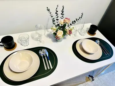 a white table with two plates and a vase with flowers at CL10100 House in Manila