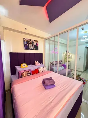 a bedroom with a large bed with a purple headboard at BTS CRIB at MOA PASAY CITY in Manila