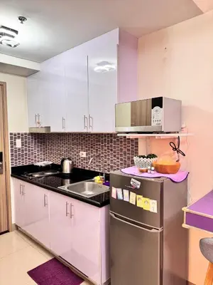 a kitchen with white cabinets and a stainless steel refrigerator at BTS CRIB at MOA PASAY CITY in Manila