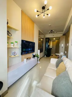 a living room with white furniture and a flat screen tv at JCS Place in Manila