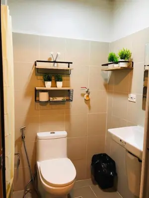 a bathroom with a toilet and some plants on the wall at JCS Place in Manila