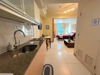 a kitchen with a sink and a living room at BGC One Uptown in Manila
