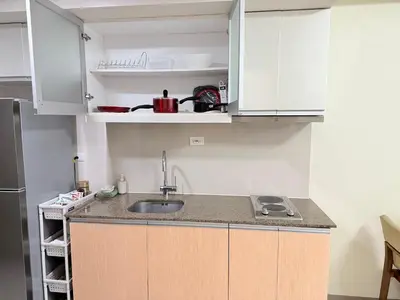 a kitchen with a sink and white cabinets at BGC One Uptown in Manila