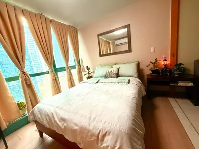 a bedroom with a large bed and a window at BGC One Uptown in Manila