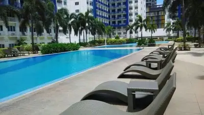 a row of chaise lounge chairs in a swimming pool at Sea Residences Mall of Asia- Jerson in Manila