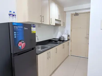a kitchen with a black refrigerator and a sink at Sea Residences Mall of Asia- Jerson in Manila