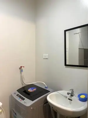 a white bathroom with a sink and a mirror at Ohana Residences by SMDC in Manila