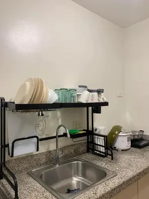 a kitchen counter with a sink and a shelf with dishes at Ohana Residences by SMDC in Manila
