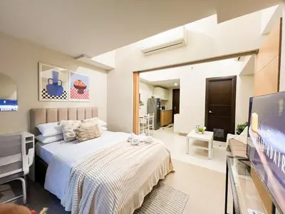 a bedroom with a bed and a flat screen tv at Stylish BGC Condo by Grand Hyatt #upt16k in Manila