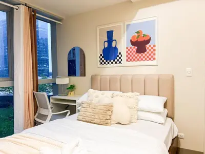 a bedroom with a bed and a desk and a window at Stylish BGC Condo by Grand Hyatt #upt16k in Manila