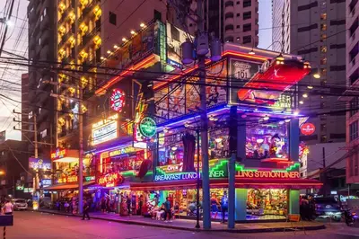 a building with neon signs in a city at night at Stylish Hip studio in the Heart of Poblacion, in Manila
