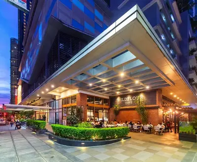 a building with people sitting at tables outside of it at Stylish condo in BGC near Uptown mall and St Lukes in Manila