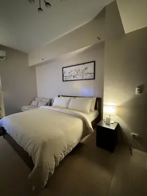 a bedroom with a large white bed and a lamp at 81 Newport Blvd Cluster 5 Unit 3F by Rechelle Nunag in Manila