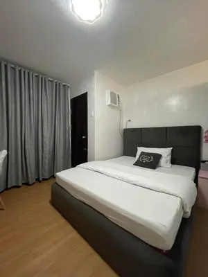 a bedroom with a large white bed with a black headboard at Hampton Staycation in Imus