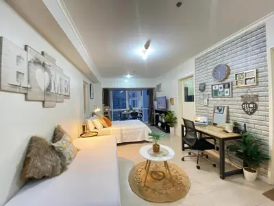 a living room with a white couch and a bedroom at South of Market Private Residences nr SM Aura BGC in Manila