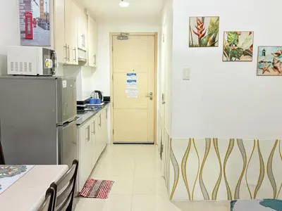 a kitchen with a refrigerator and a table and a door at Sea Residences MoaPasay City By Jerson in Manila