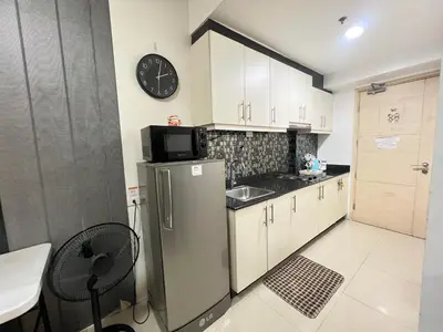 a kitchen with a refrigerator and a clock on the wall at Sea Residences MoaPasay City By Jerson in Manila