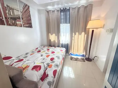 a bedroom with a bed and a lamp in it at Sea Residences MoaPasay City By Jerson in Manila