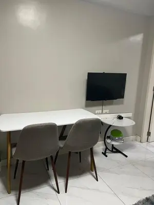 a white table with two chairs and a television at Monarch parksuites 1bedroom with free pool access in Manila