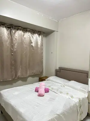 a pink stuffed animal sitting on top of a bed at Monarch parksuites 1bedroom with free pool access in Manila