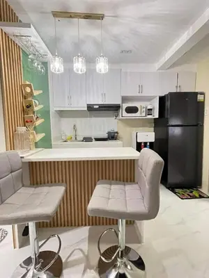 a kitchen with a black refrigerator and two bar stools at 1 BR Nordic Suite with Netflix, Disney, Prime in Manila