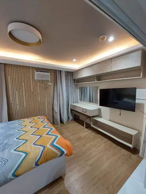 a bedroom with a bed and a flat screen tv at 1 BR Nordic Suite with Netflix, Disney, Prime in Manila